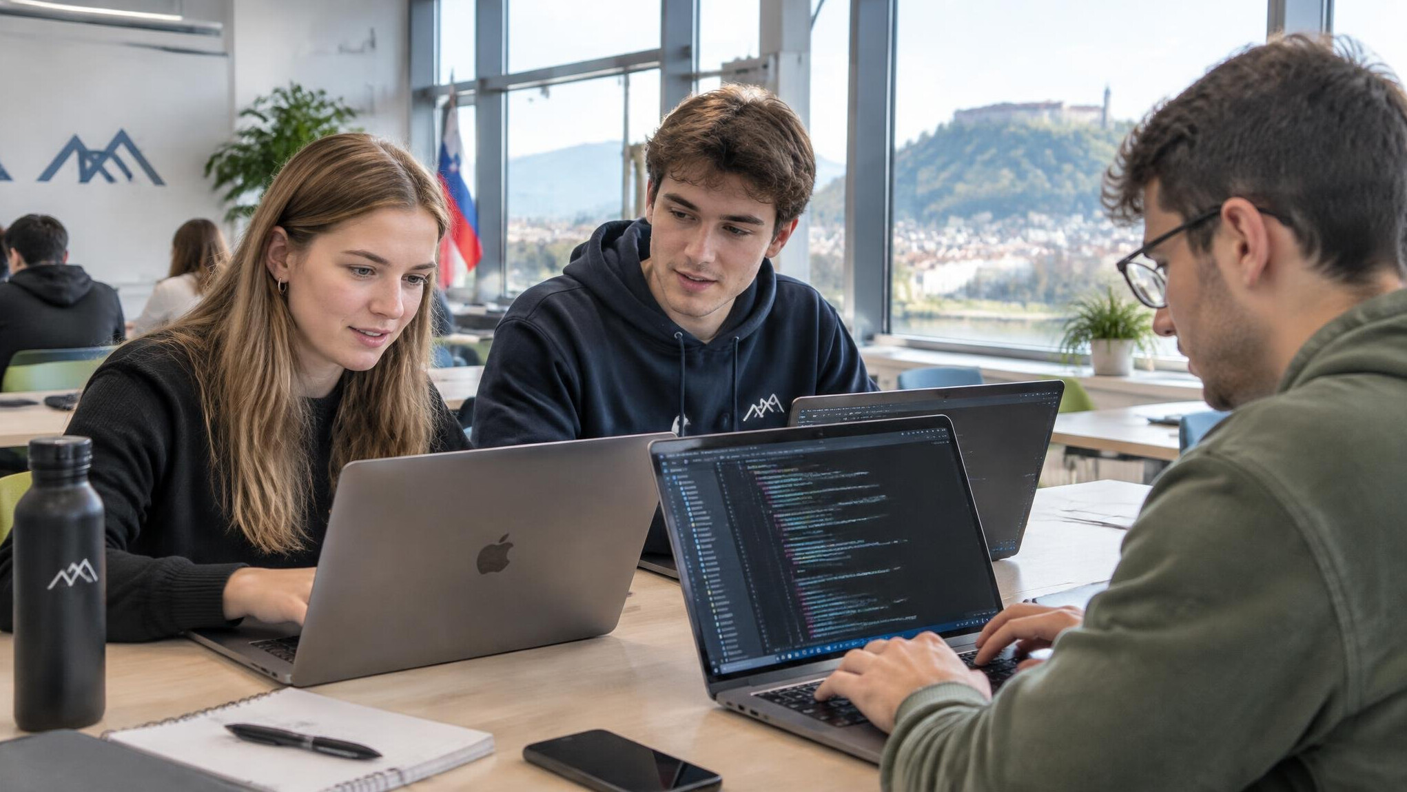 Group of young adults learning programming together on laptops in a modern classroom
