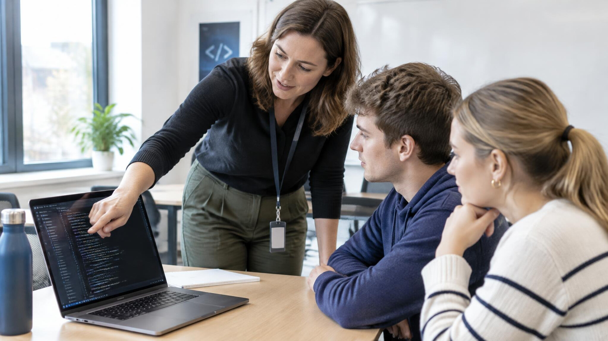 Instructor explaining code on a laptop to a small group of students