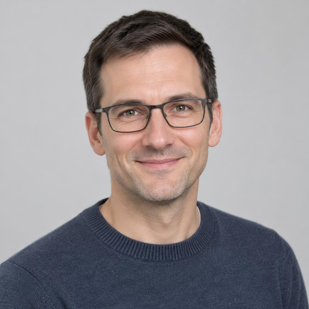 Studio portrait of a Slovenian man in his 40s with glasses smiling